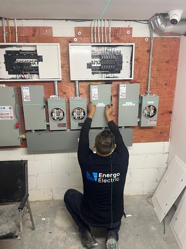 Professional electrician installing Eaton electrical panels and meter sockets using a laser level.