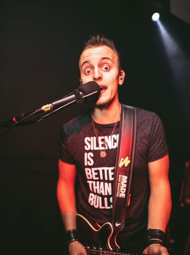 Guitarist Lucas Vianna playing a Red Special Brian May guitar while singing into the microphone.