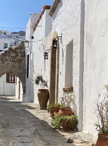 a man standing on a stone path in a narrow alley in Lindos village in Rhodes Greece