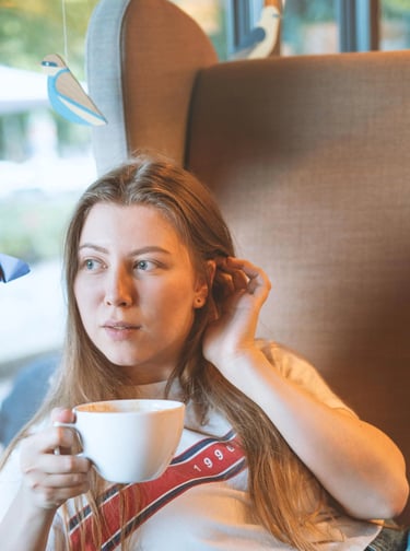 90s style portait picture of a young girl in a coffee shop drinking coffee in a big armchair  