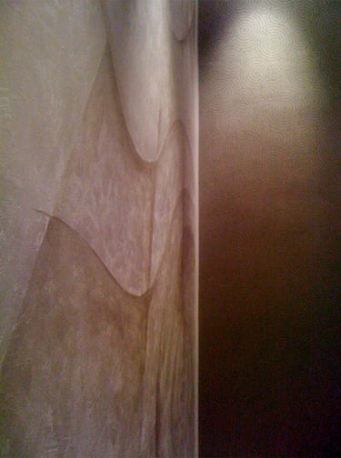 Dimly lit large silver mural with wavy lines in an elegant office.