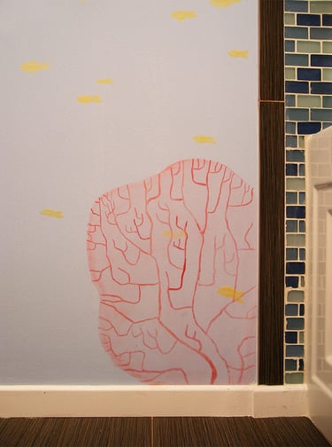 Hand-painted red coral and yellow fish painted in a contemporary style in a kid's bathroom.