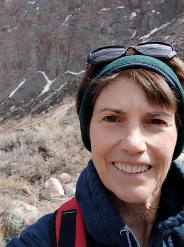 Susan Rensberger in the rugged Andes mountains wearing a headband and sunglasses on her head