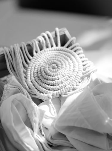 Handmade off-white cotton rope trivet or coaster with spiral design and fringe.