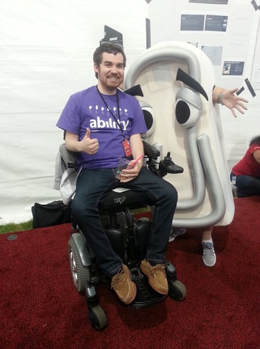 Sean in a purple "Ability" t shirt next to a life-size Microsoft Clippy costume