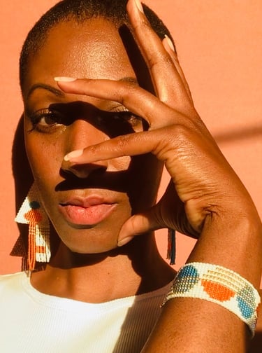 A black woman wearing a pair of matching beaded earrings and beaded bracelets
