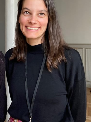 Julia Braun lächelt freundlich; braunes schulterlanges Haar, schwarzer Rollkragenpullover 