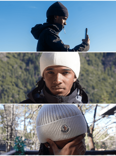 A man wearing a Moncler knit beanie and winter jacket takes photos in a mountain landscape.