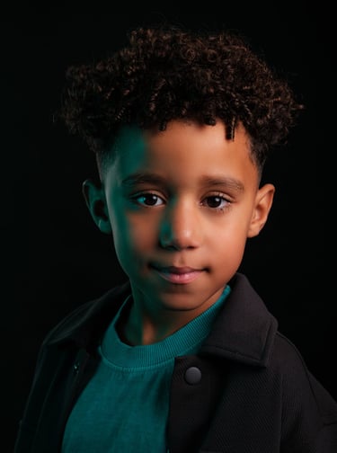 a young boy with a black jacket and a green sweater
