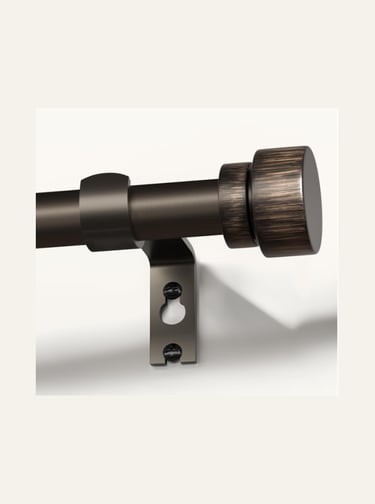 Antique bronze curtain rod with a decorative cylinder finial mounted on a wall bracket.