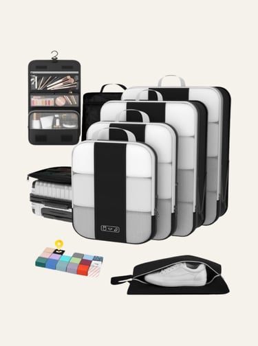 Set of black and white packing cubes, hanging toiletry bag, and shoe bag for organized travel luggage.