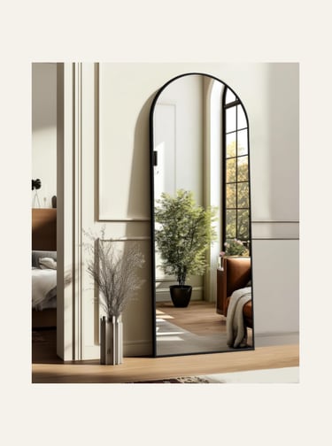 Modern black framed arched full length floor mirror in a bright bedroom interior.