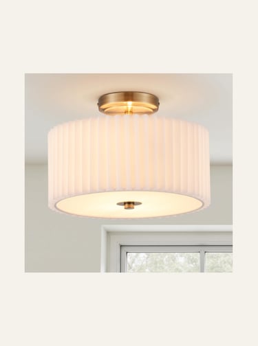 Modern semi-flush mount ceiling light with a pleated white fabric drum shade and antique brass finish.
