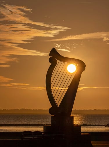 Raising Sun illuminating a large harp sculpture erected for Fleadh Cheoil on Wexford sea front.