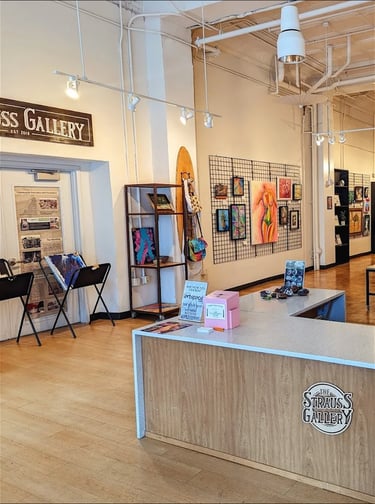 The interior of Strauss Gallery art studio featuring local artwork on wire grid walls and a modern reception desk.