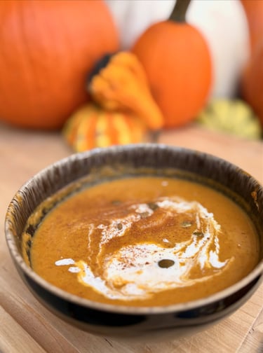 pumpkin bisque with a swirl of cream and pupkins in the background