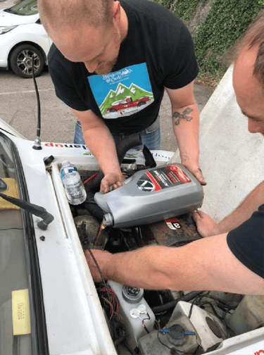 a man and a woman working on a car engine