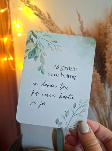 Afirmacijos kortelė su tekstu "Aš girdžiu savo baimę" laikoma rankoje