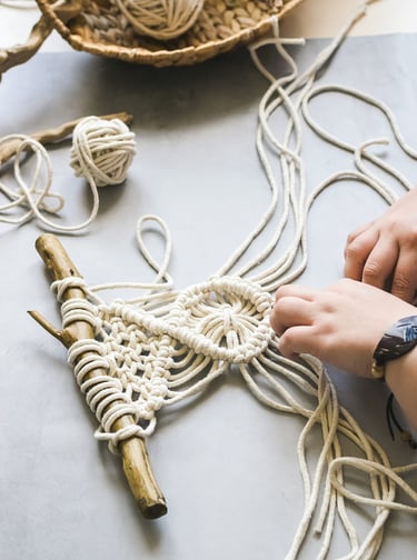 proyecto pequeño de macrame en blanco sobre un tronco de madera