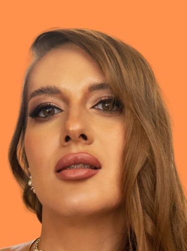 Woman with professional glam makeup and brown eyes posing against an orange background.