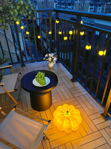 Cozy small balcony with space-saving furniture, soft cushions, potted plants, and warm evening light.