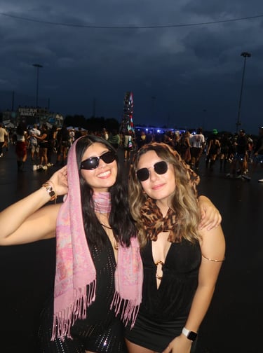two women in black outfits standing in front of a ferris wheel