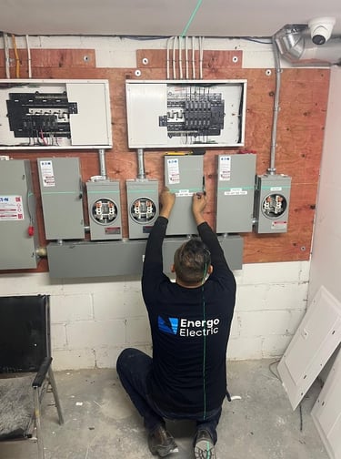 Professional electrician installing Eaton electrical panels and meter sockets using a laser level.