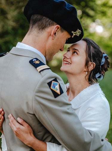 Une mariée souriante enlace son époux, vêtu d'un uniforme militaire à Bois-d'Oingt