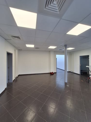 Une photo avant transformation de l'ancien showroom avec des murs blanc et un sol gris 