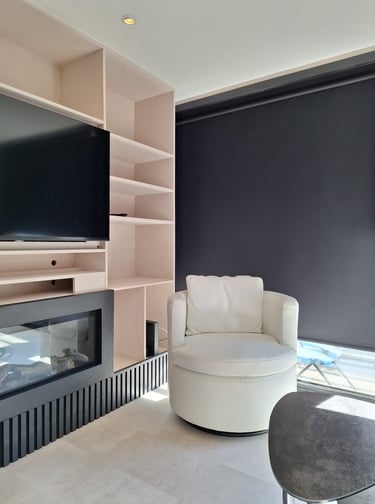 Zoom sur un mobilier sur-mesure beige avec des lattes de bois noires et un fauteuil blanc