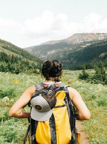Person hiking through a green mountain valley with a backpack