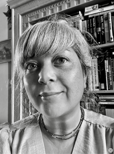 Black and white portrait of Annette in front of a bookshelf.