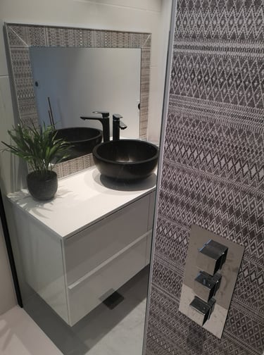 Salle d'eau, meuble blanc avec vasque à poser noire ronde, robinetterie de douche encastrée chromé.