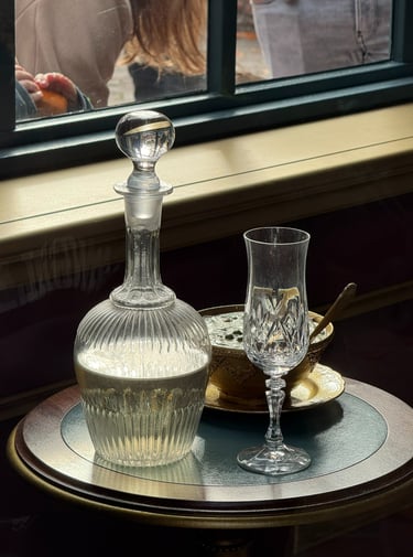 Elegant crystal glass decanter and wine glass set on a table by a window.