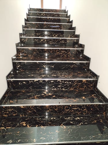 Polished black and gold marble staircase with anti-slip metal stair nosing in a modern home interior.