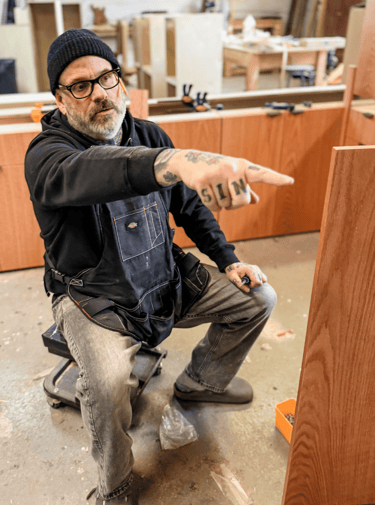 Master woodworker and artisan craftsman giving direction to team in Detroit workshop.