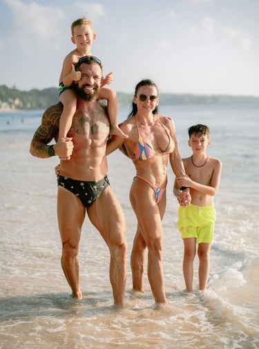 Family walking together through shallow ocean water during a sunset family photography session at Dreamland Beach Bali.