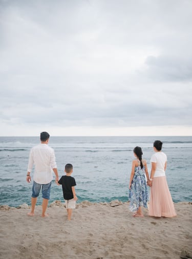 Family standing together along the cliffside coastline of Melasti Beach Bali during a relaxed family photography session