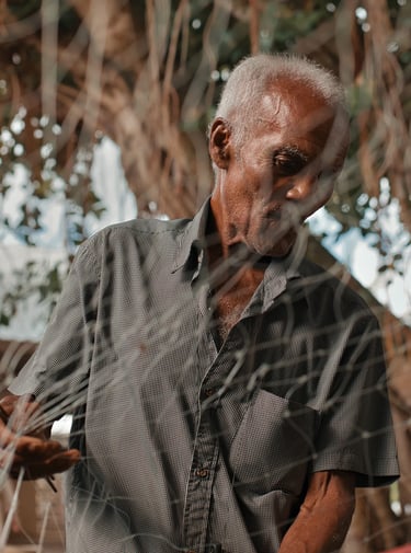 Portrait of elderly fisherman through fishing net, Mahebourg, Mauritius