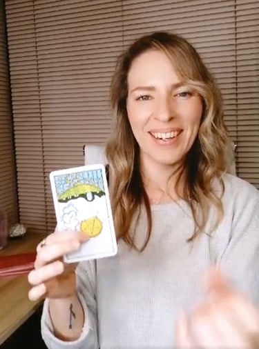 Natalie holding the Ace of Pentacles reversed during a live tarot reading.