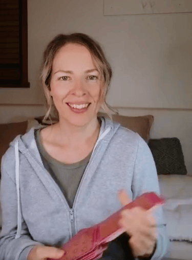 Natalie holding the Five of Pentacles reversed in a live tarot reading.