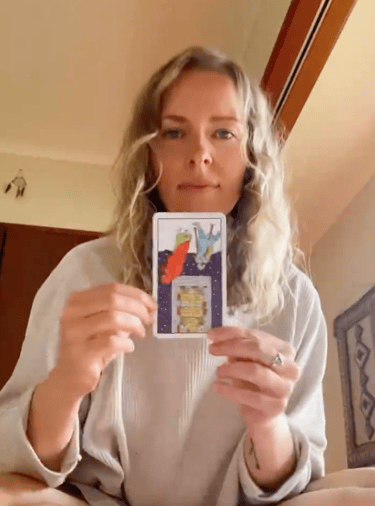 Natalie holding the Five of Pentacles reversed in a live tarot reading.