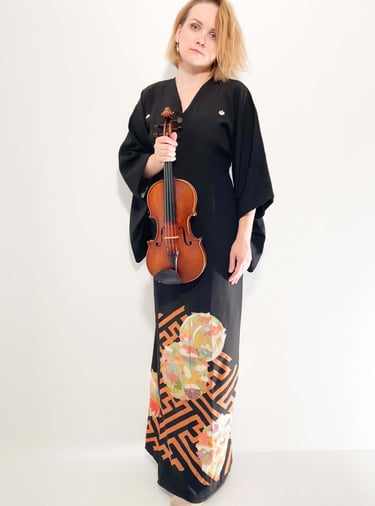 Violinist Zydre in a black kimono-style dress holding a violin, contemporary classical artist portrait