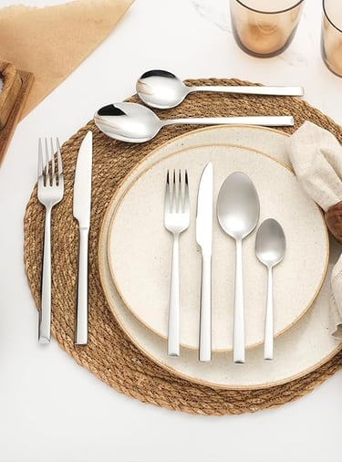 White stainless steel cutlery set styled on natural woven placemat.