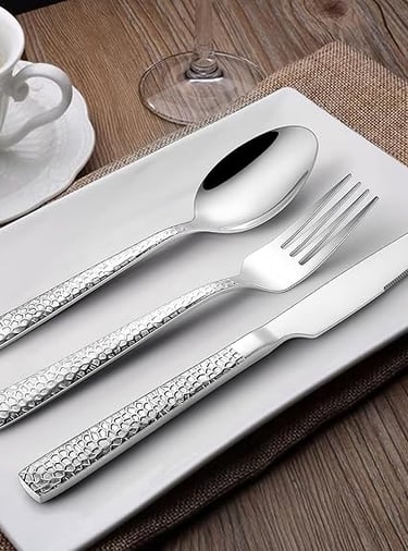 Silverware cutlery set arranged on modern white ceramic tableware.