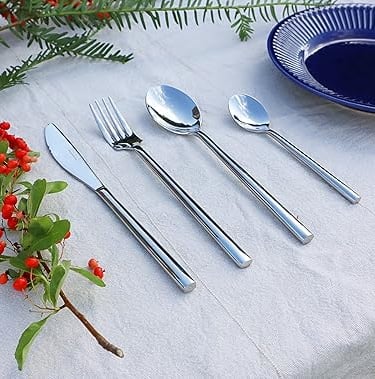 Stainless steel cutlery set placed on a fresh bright white tablescape.