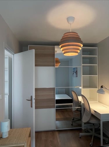 a bedroom with a desk and a bed in the background