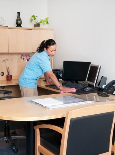 a woman cleaning a desk in an office setting