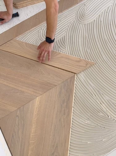 Pose de parquet collé sur sous-couche encollée avec alignement soigné des lames