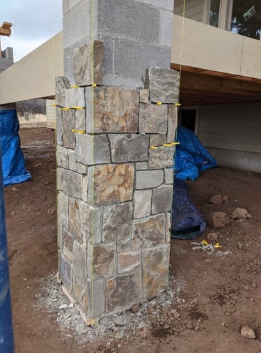 Habillage d’un pilier en blocs de béton avec parement en pierre naturelle